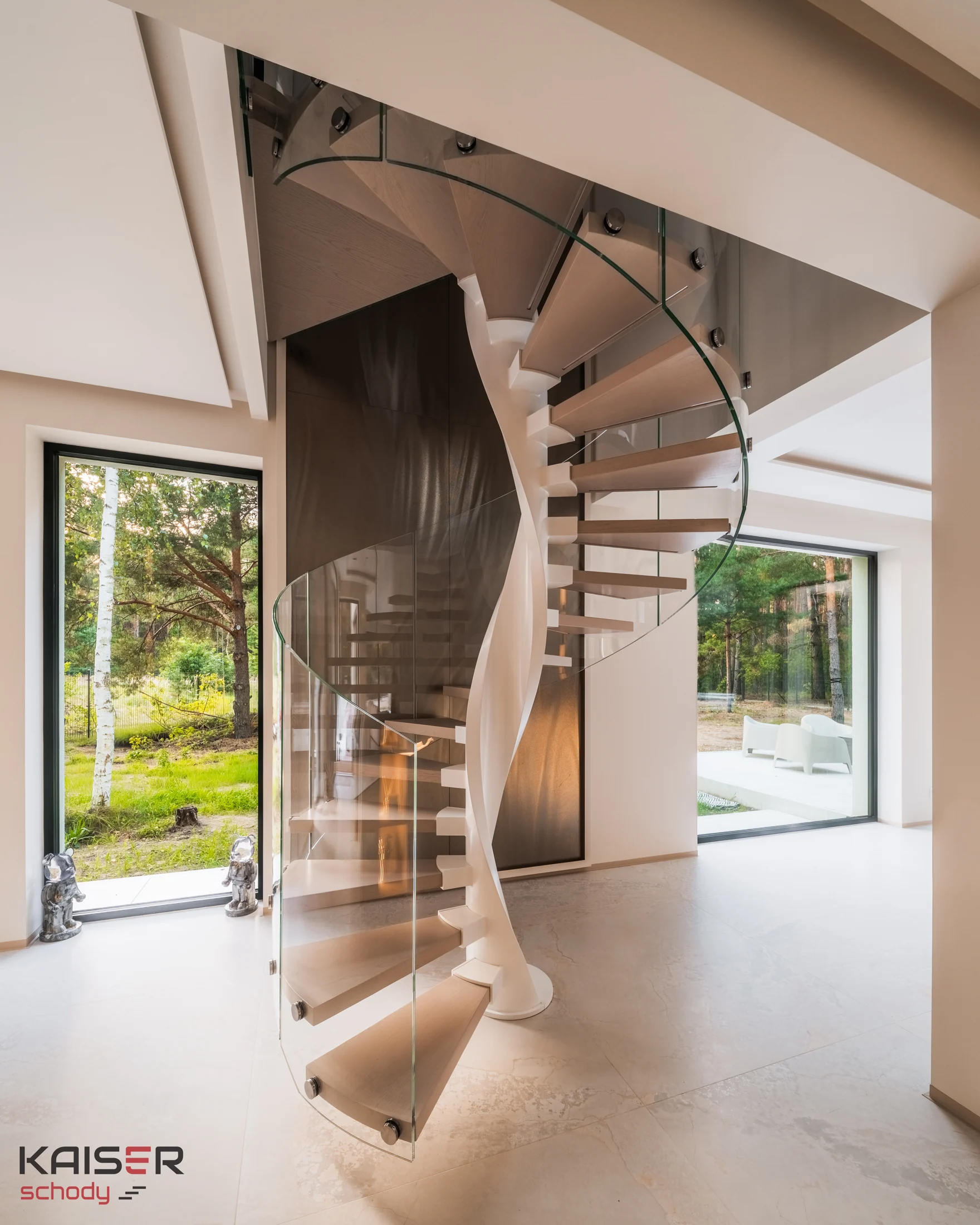 Light-coloured KAISER spiral staircase with a glass balustrade in an interior